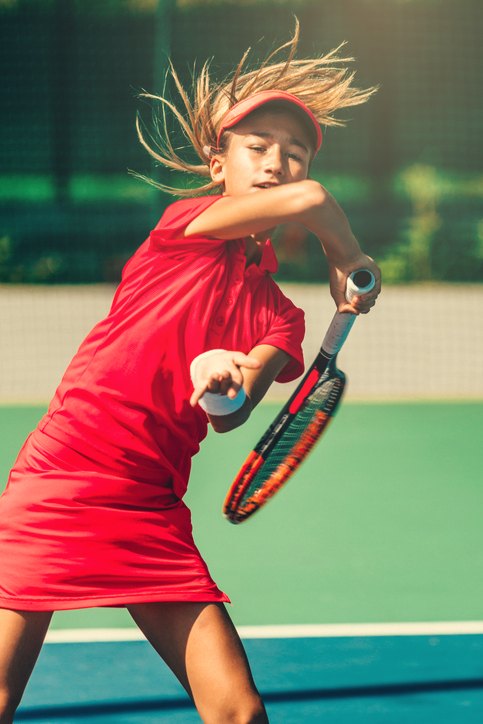A young tennis player hitting a powerful forehand, fully focused