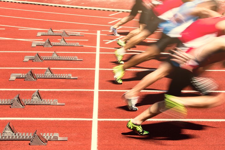 Sprinters exploding out of the starting blocks on a running track
