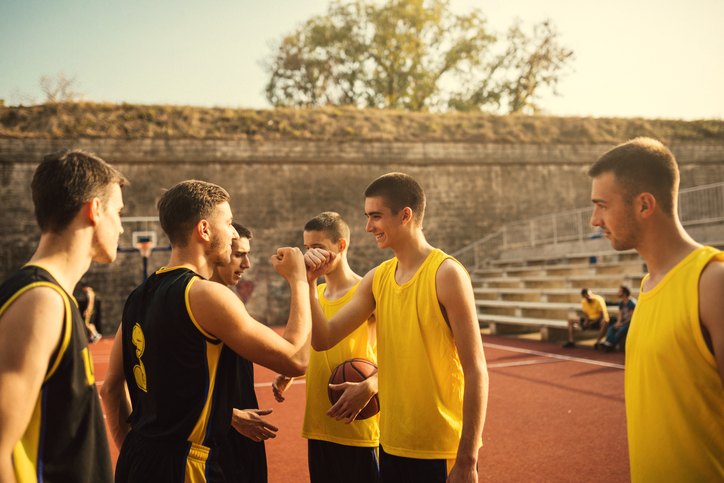 Young basketball players bumping fists with their opponents after a game